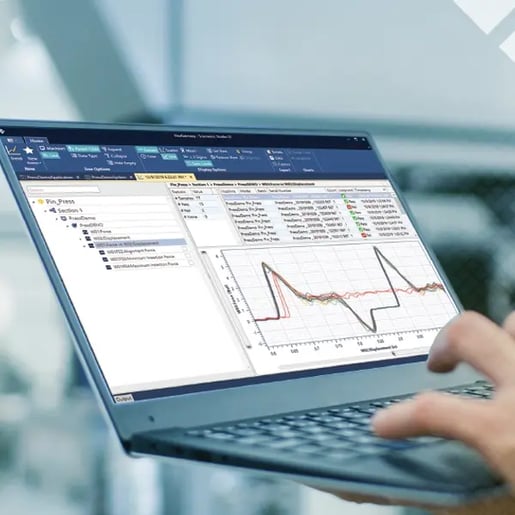 One hand holding a small laptop featuring a Sciemetric Studio screen with waveforms while the other hand types on the keyboard