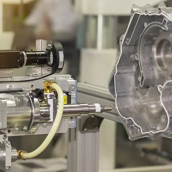 A machine applying adhesive to the edges of a gasket on a production line