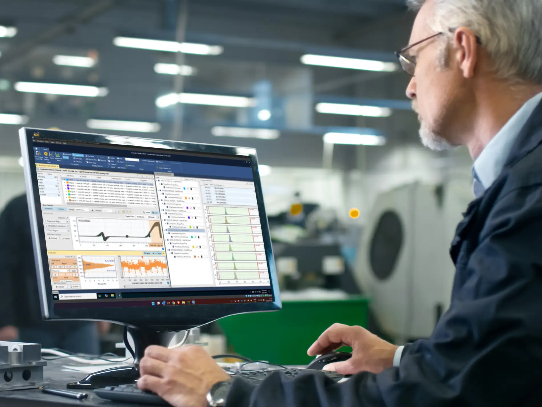 Older man on the right sitting at a desk in a manufacturing environment looking at a computer monitor with Sciemetric Studio data