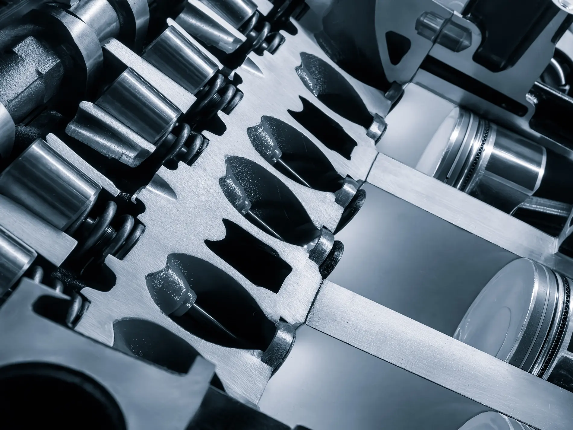 A close up of a car engine with the pistons and cylinders visible.