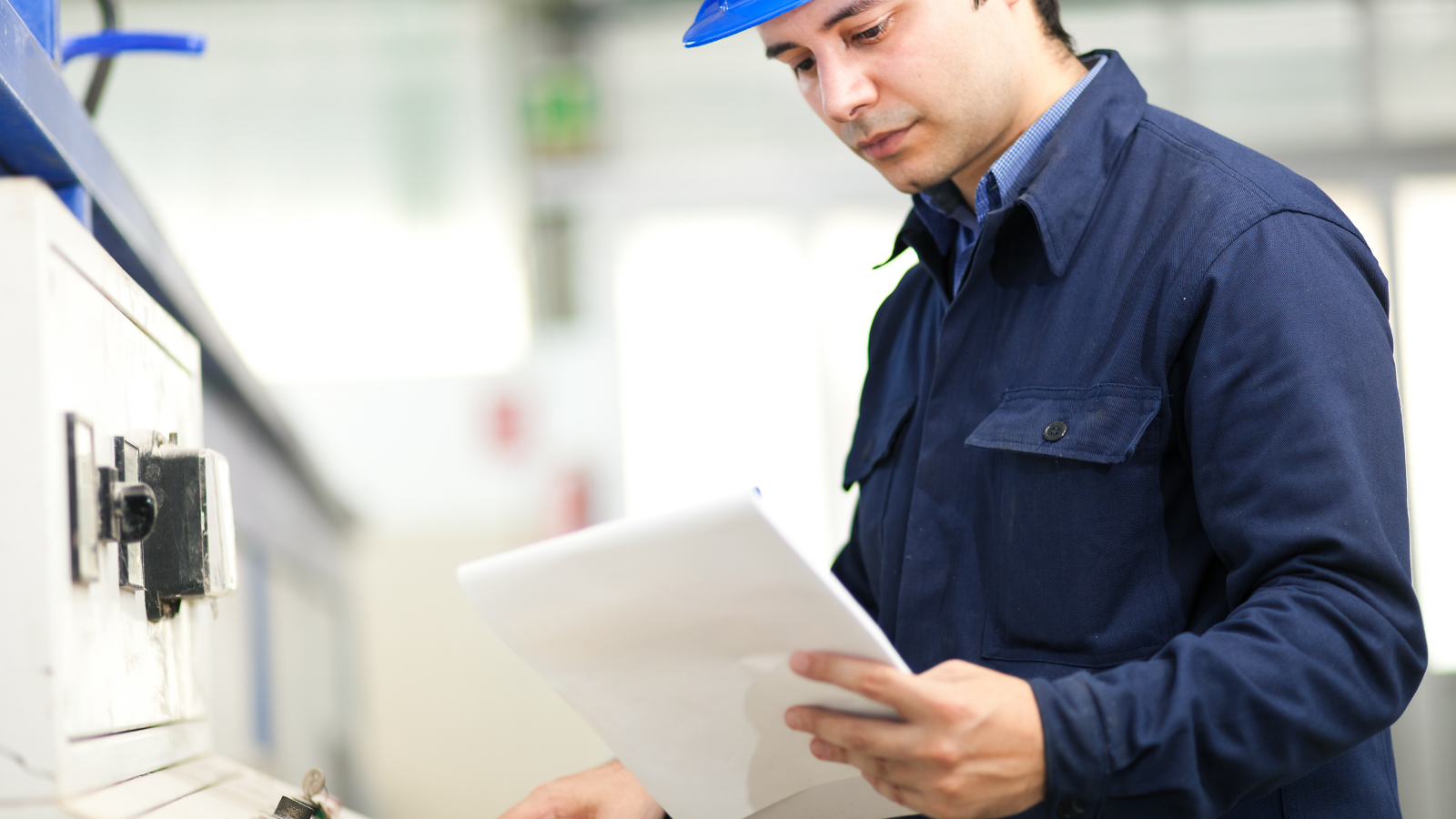 Man on manufacturing line looks at papers 