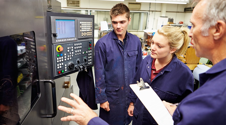 Engineer Teaching Apprentices To Use Computerized Lathe