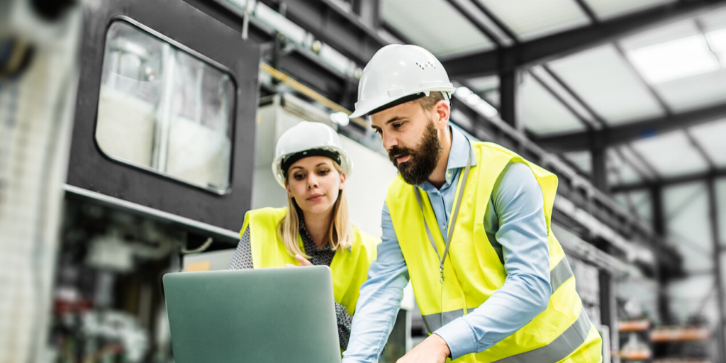 engineers on plant floor looking at computer screen