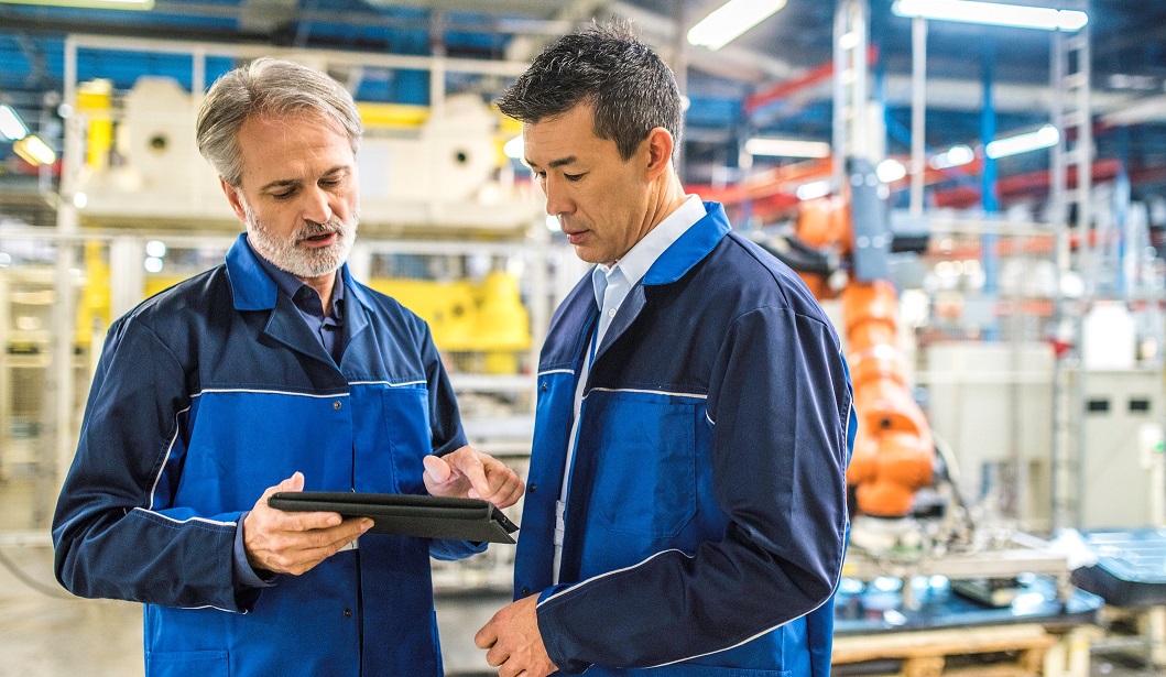 men on production floor viewing data on tablet screen